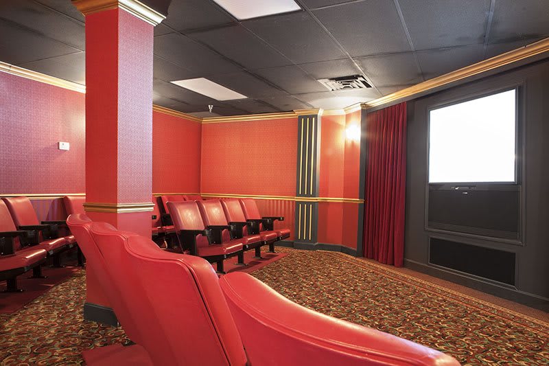 A cozy home theater with red seating and a large screen.