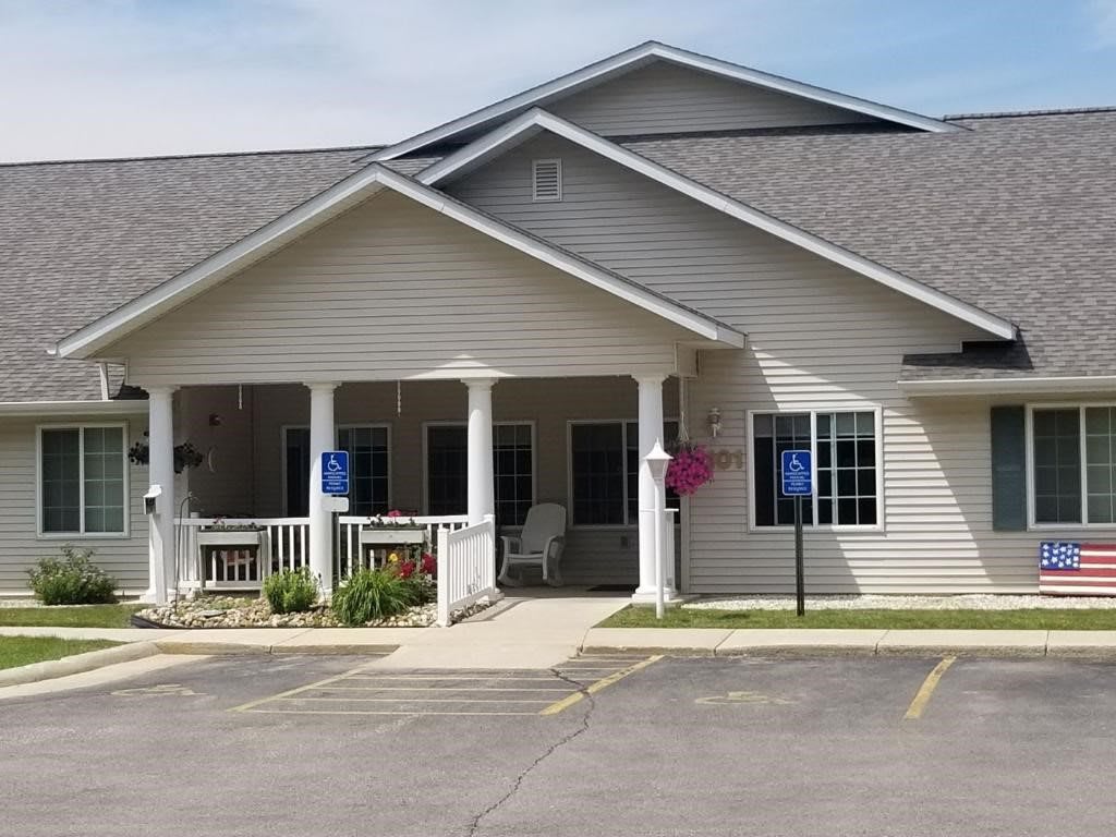 A single-story house with a front porch and a parking area in front.