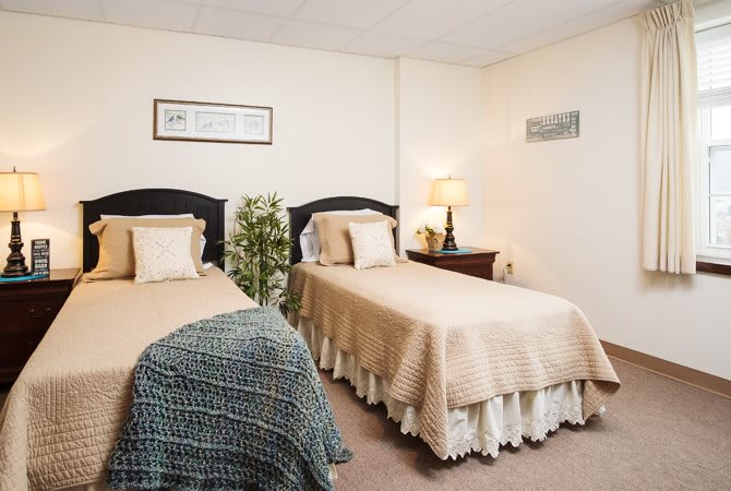A cozy bedroom with twin beds, complete with lamps and decorative pillows.
