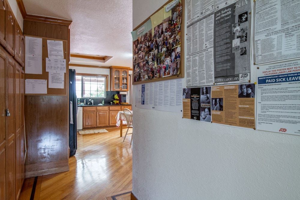A view of a kitchen from a hallway adorned with posters and a wooden floor.