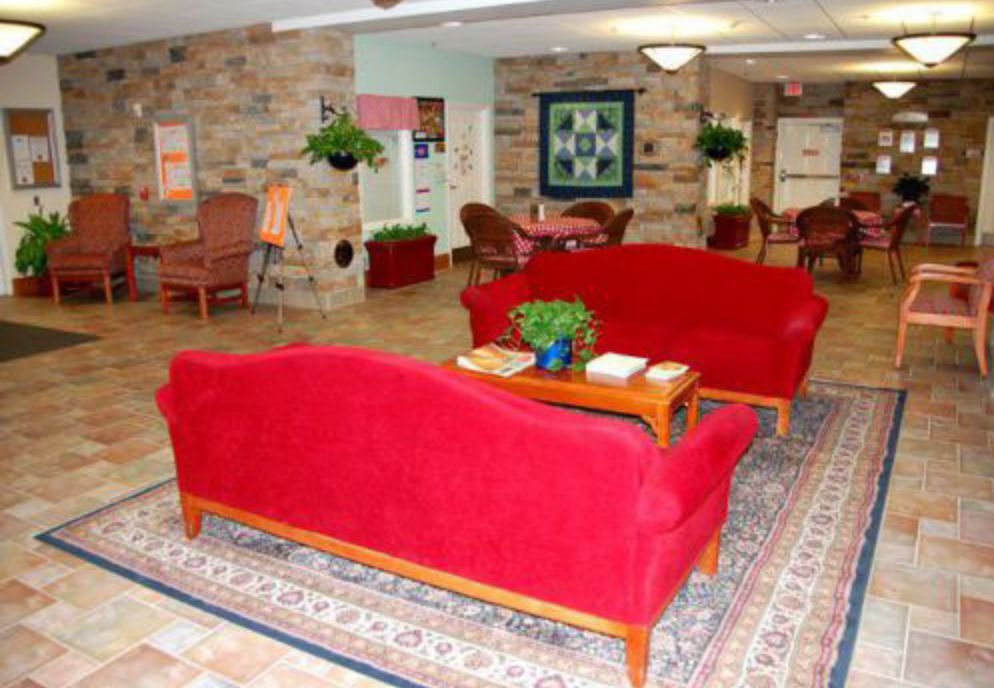 A cozy lobby area featuring vibrant red sofas and a decorative rug.