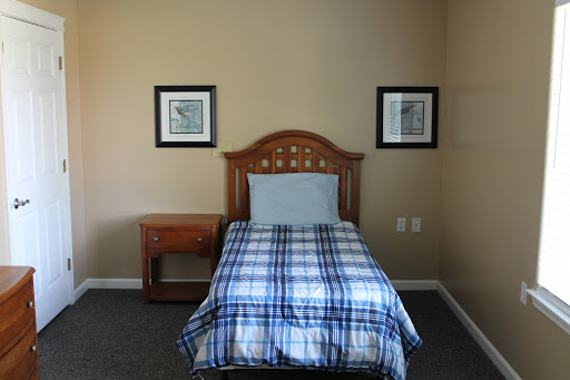 A cozy bedroom featuring a single bed with a plaid blanket and framed wall art.