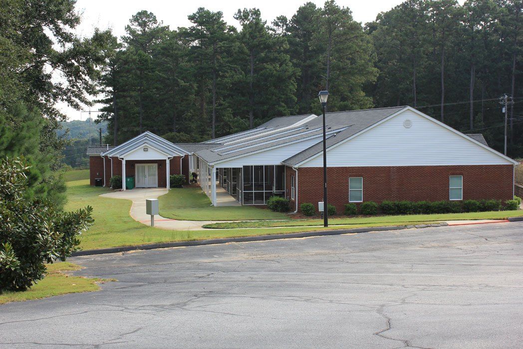 A brick office building surrounded by trees and a paved road.