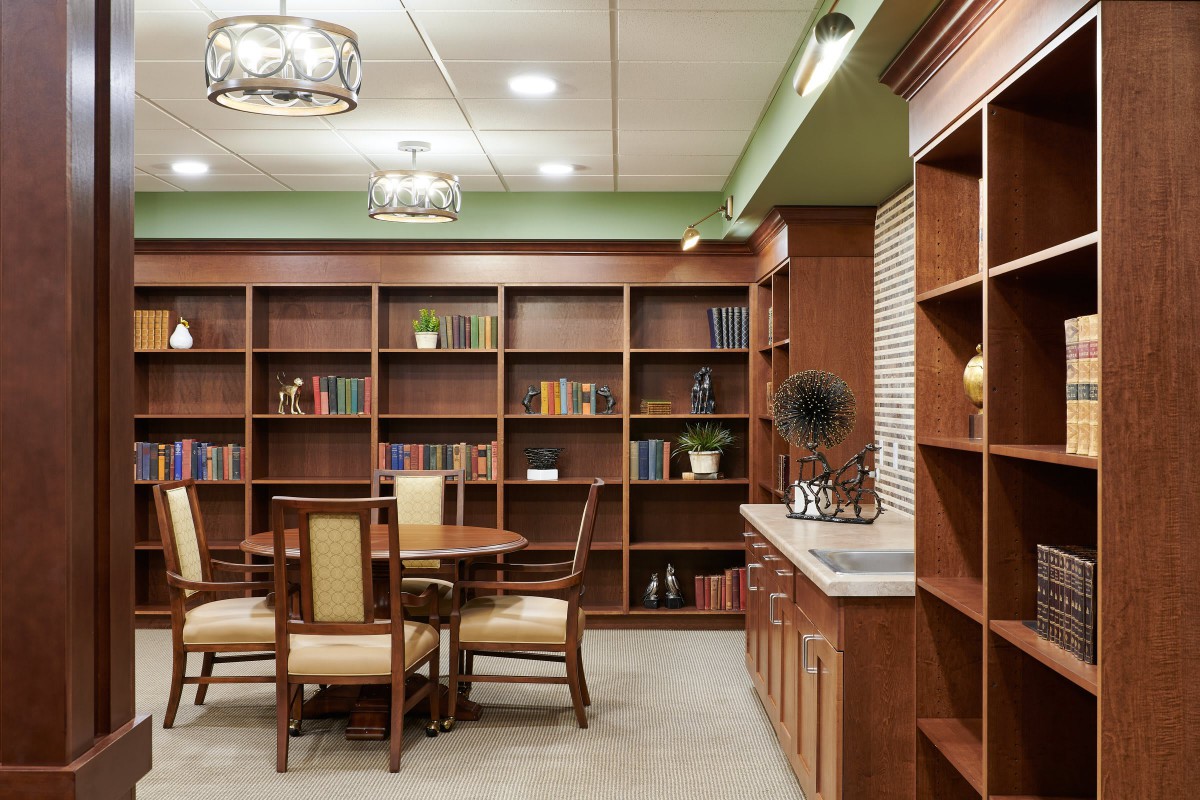 A cozy library with wooden bookshelves, a round table, and chairs for reading and studying.
