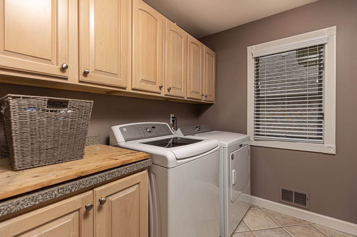 A well-organized laundry room featuring a washing machine, dryer, and wooden cabinets.