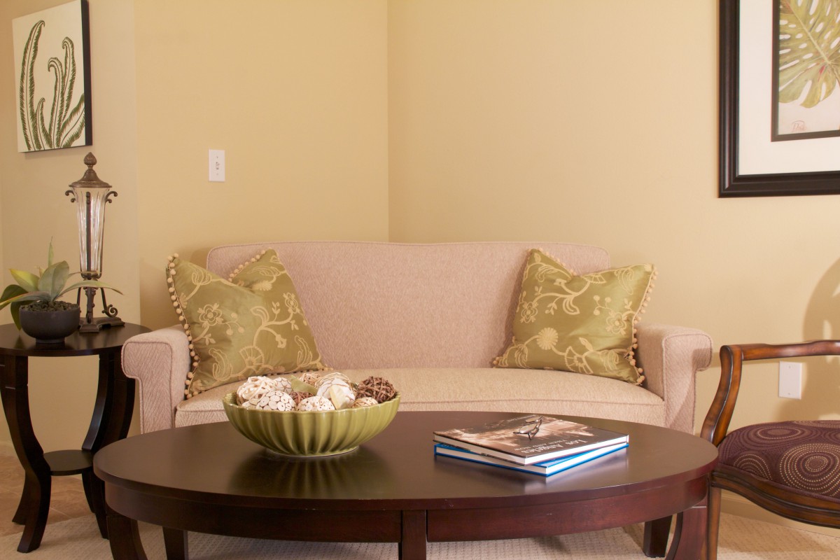 A cozy living room setup with a beige sofa, decorative pillows, a wooden coffee table featuring a bowl and books.