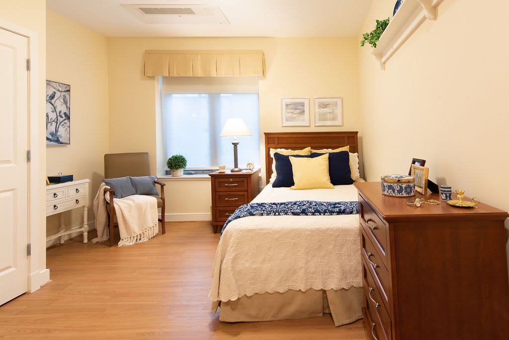 A cozy bedroom with a single bed, wooden furniture, and soft lighting.