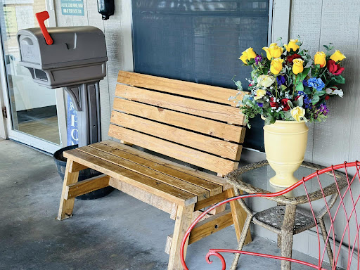 A cozy corner featuring a wooden bench and a vibrant vase of flowers.