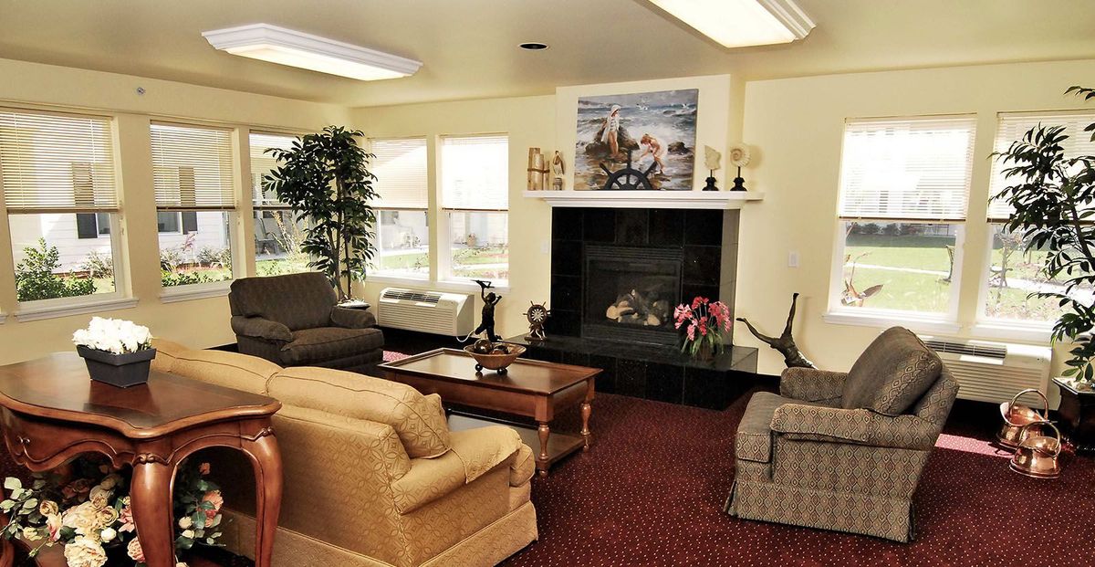A cozy living room with sofas, a coffee table, and a fireplace surrounded by decorations.