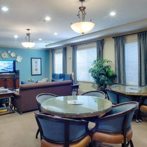 A cozy living room with a seating area, round dining table, TV, and warm lighting.