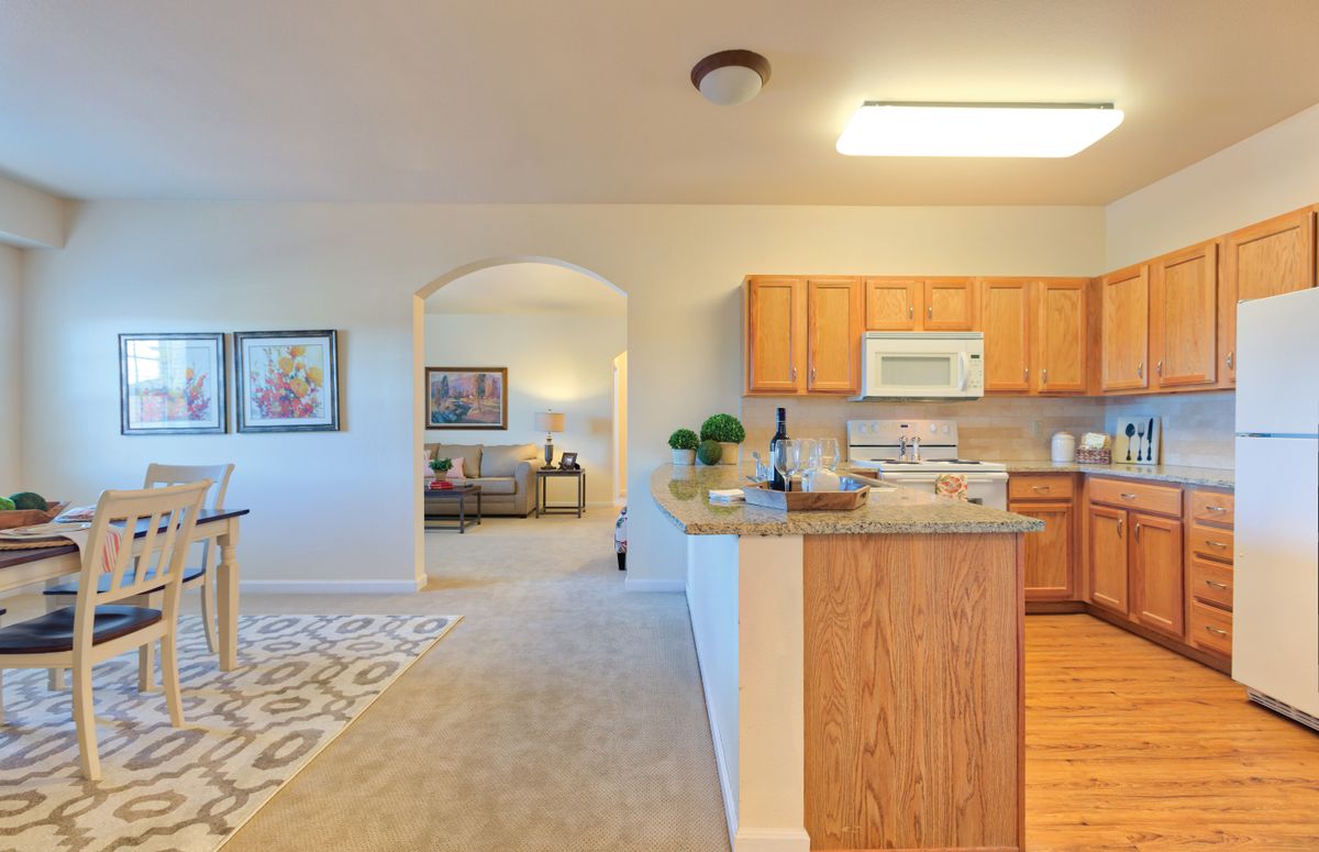 A cozy kitchen opens into a comfortable living room with modern decor and bright lighting.