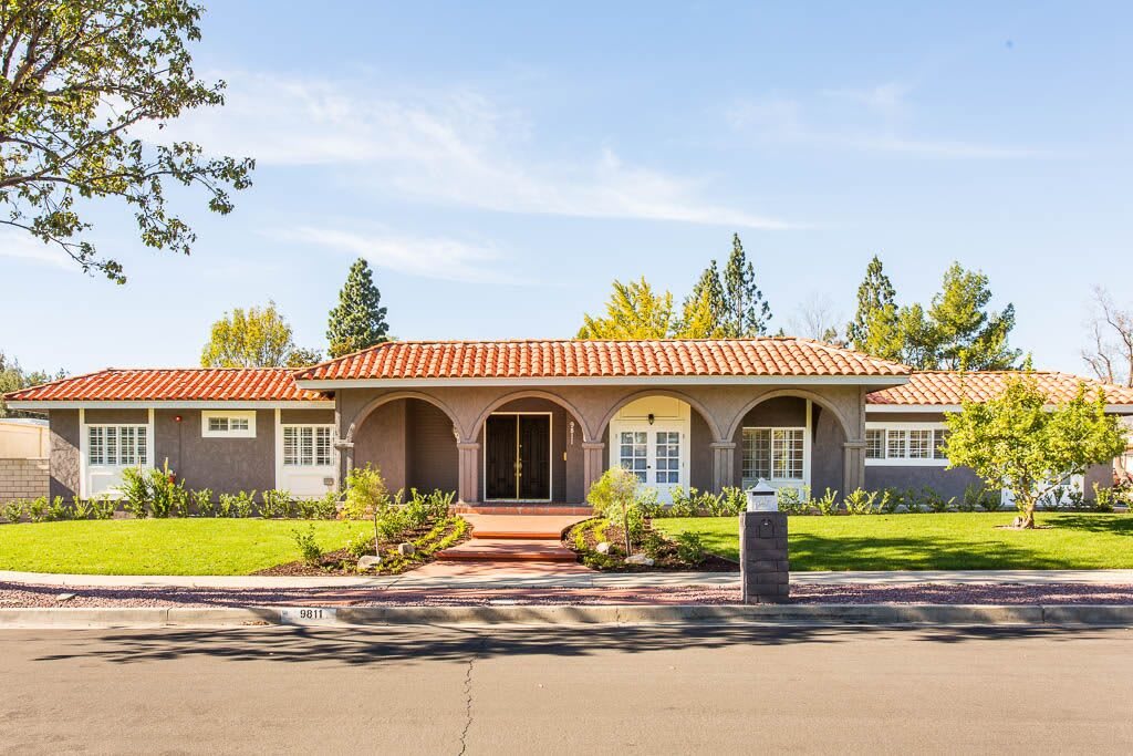 A beautiful single-story house with a tiled roof and front yard landscaping on a sunny day.