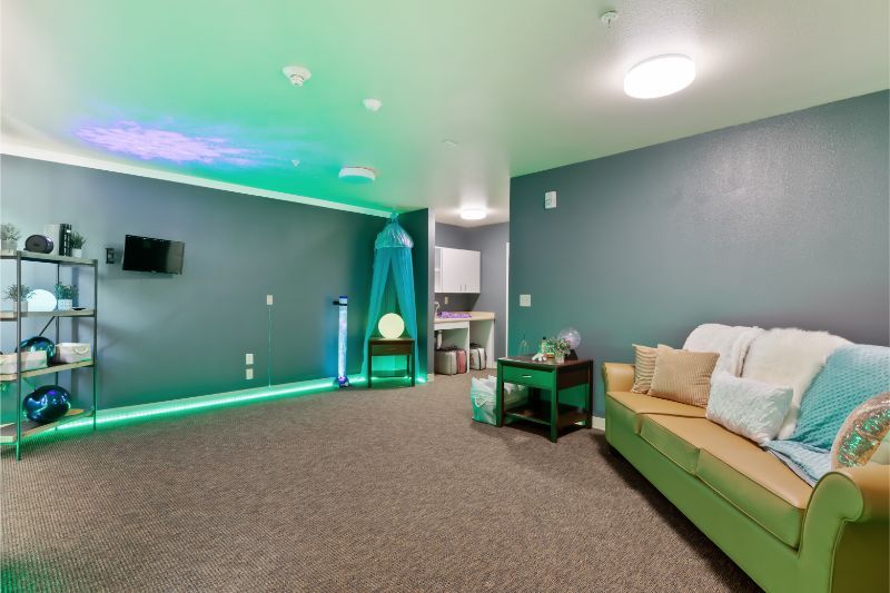 A modern living room with ambient green lighting and cozy furniture.