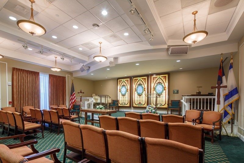 A religious setting with rows of seating and decorative stained-glass windows.