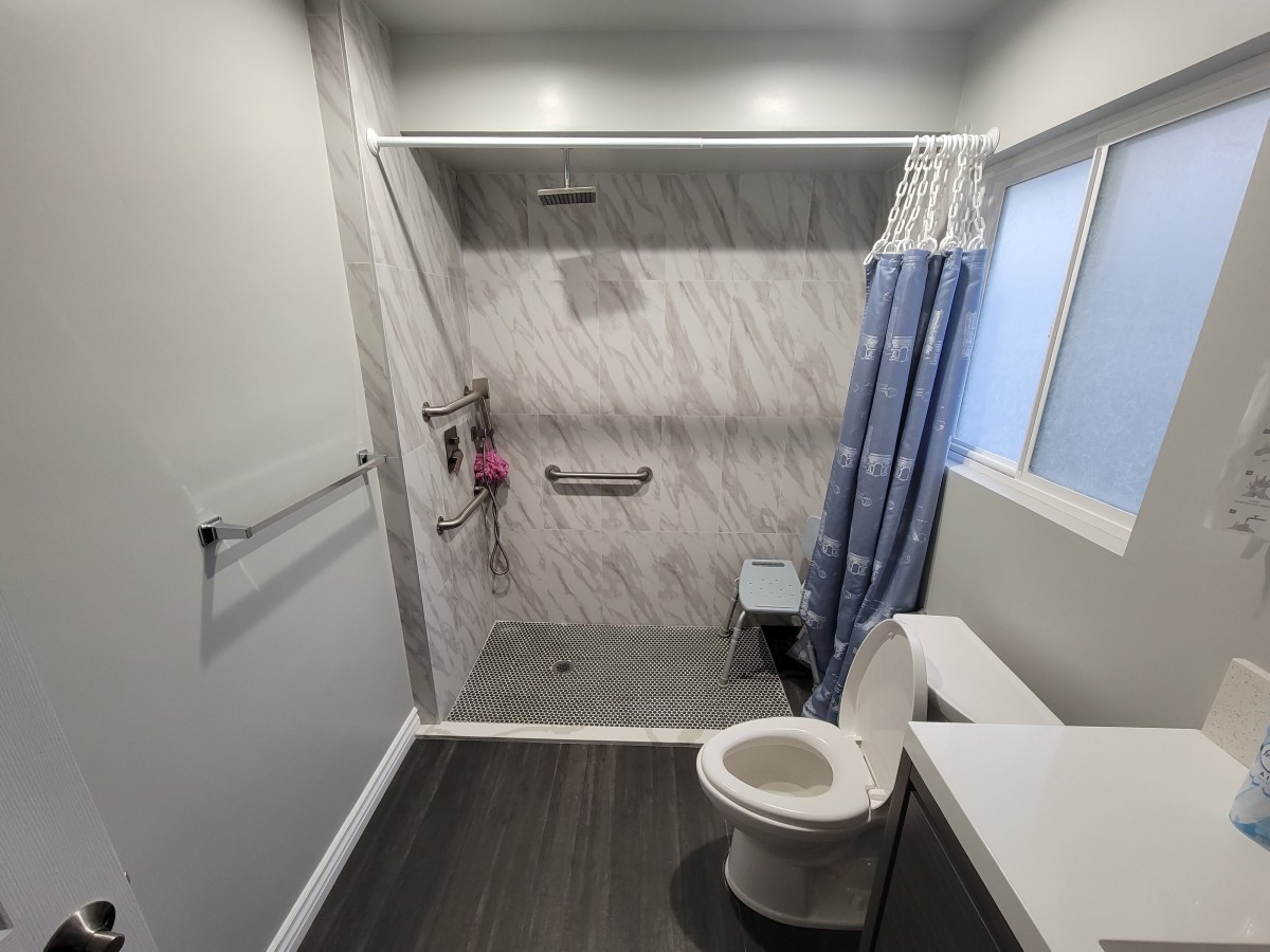 An accessible bathroom with a shower, toilet, and grab bars.