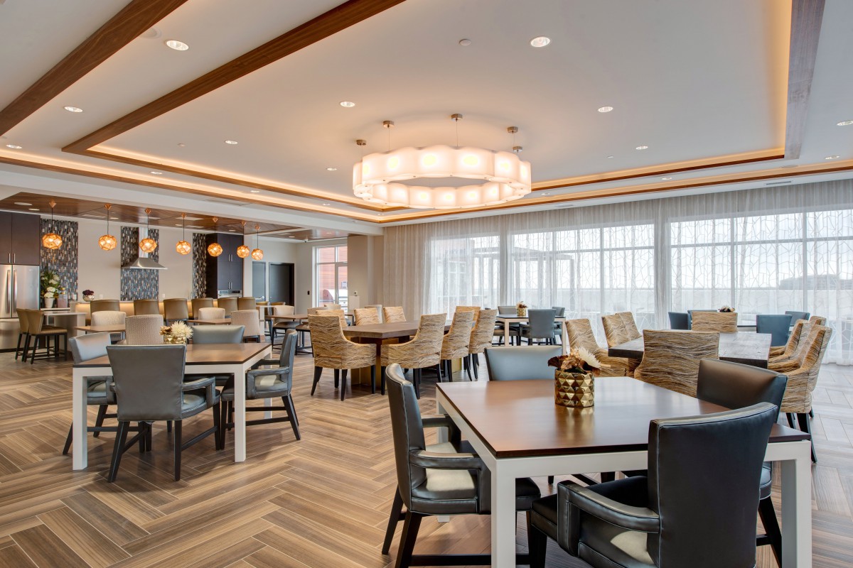A spacious and elegantly designed dining room with modern furniture and a large chandelier.