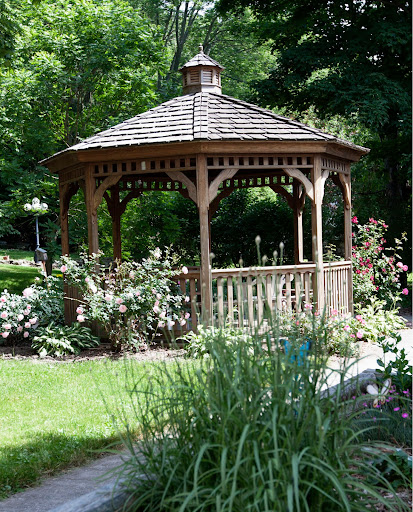 A charming wooden gazebo surrounded by lush greenery and vibrant flowers.