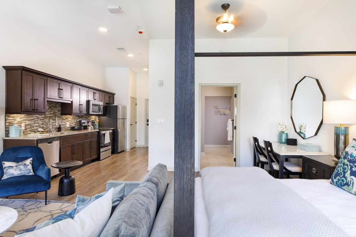 A modern studio apartment featuring an open floor plan with a cozy kitchen and elegant bedroom area.