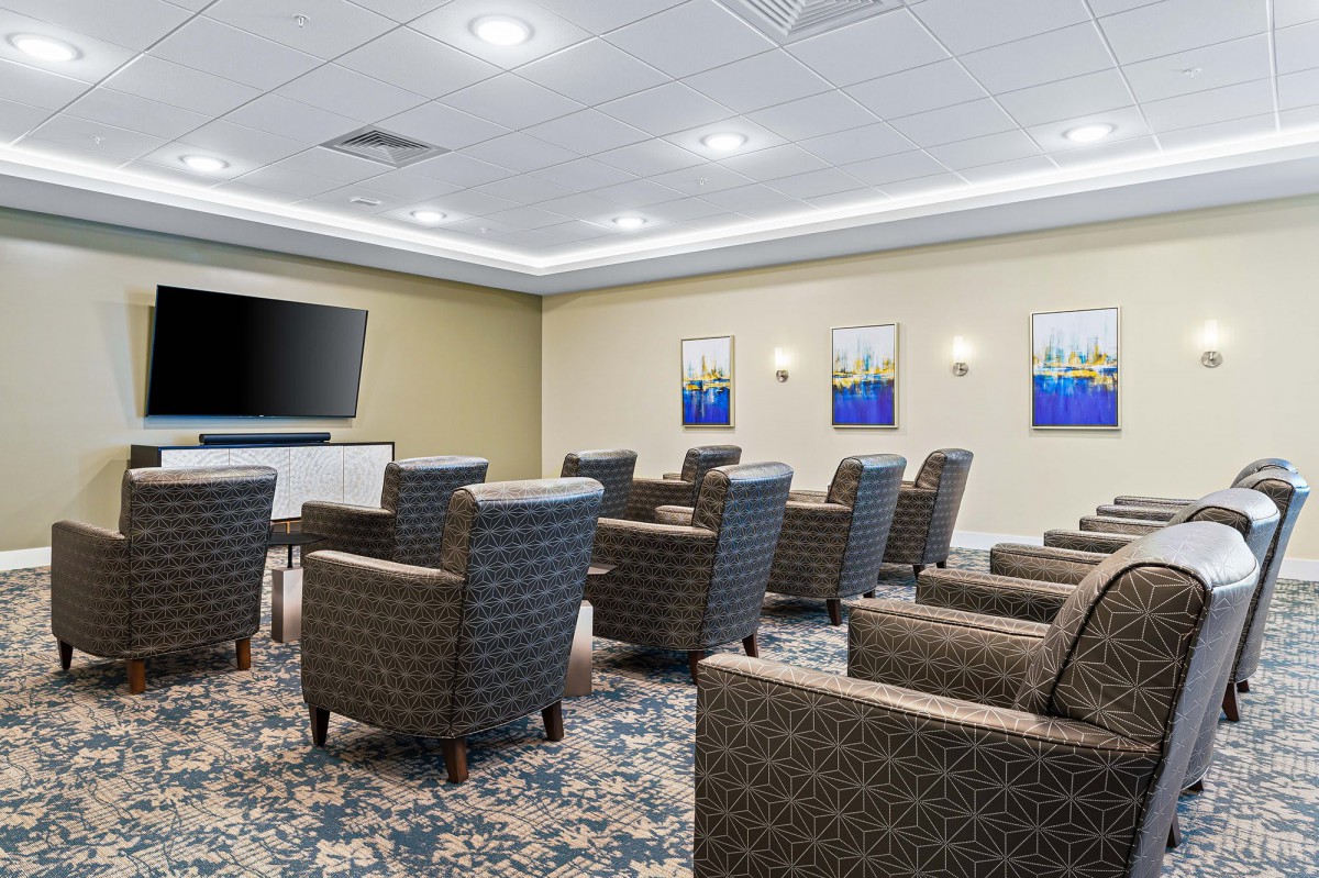 A neatly arranged conference room with a large TV screen, comfortable chairs, and artistic paintings on the walls.