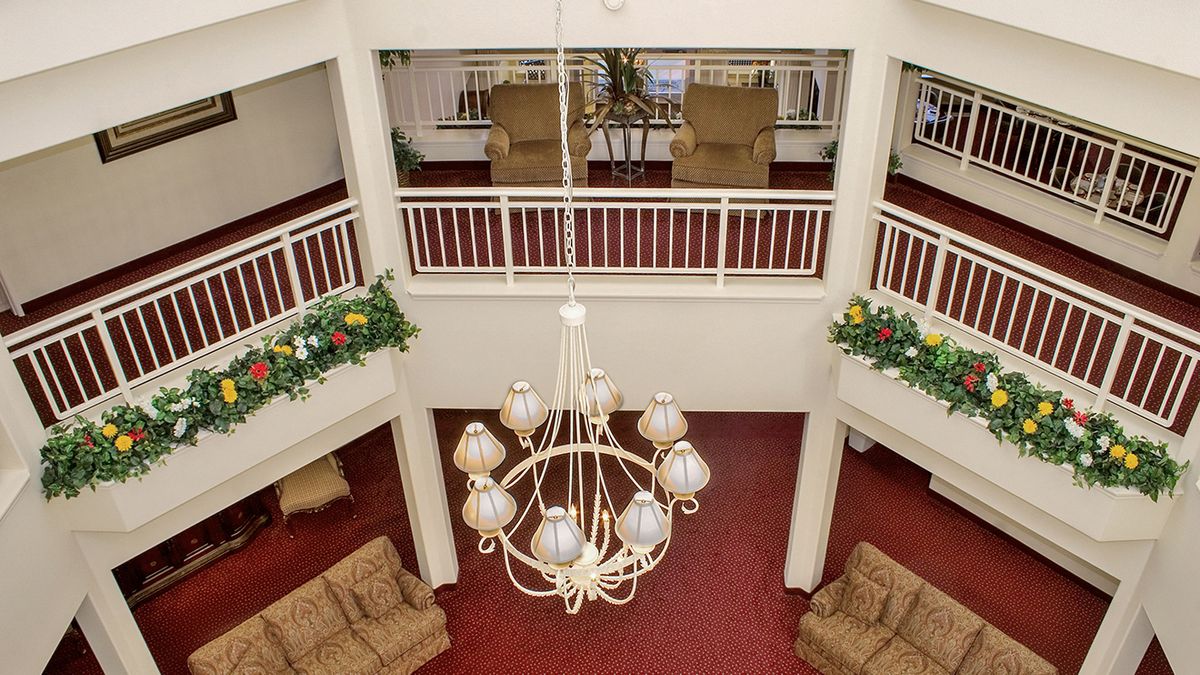 A spacious lobby with a central chandelier, comfortable seating, and decorative plants.