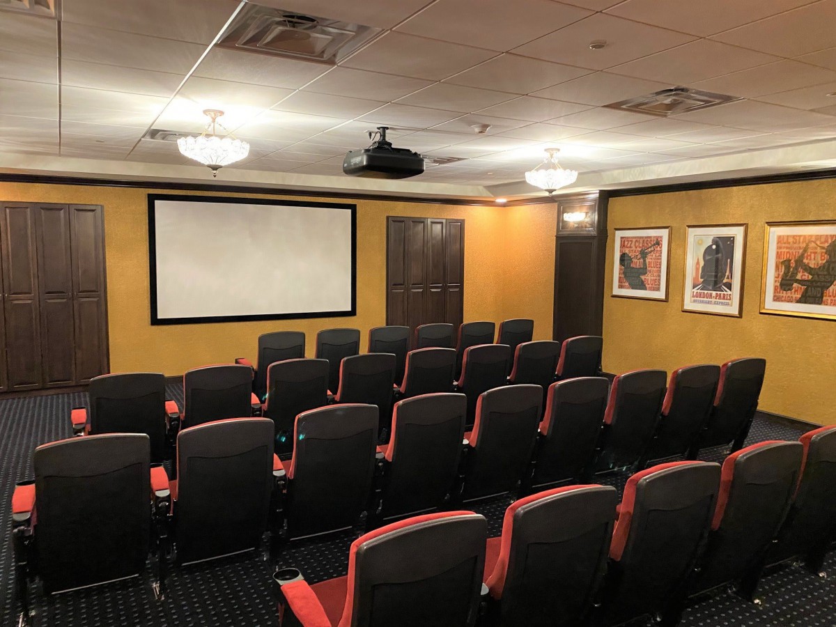 A small theater room with rows of seats facing a large screen.