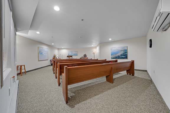 An empty chapel with wooden pews and artwork on the walls.