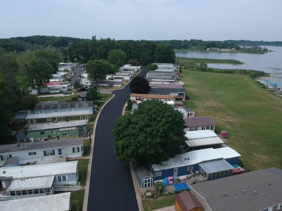 Aerial view of a residential area with mobile homes and a nearby lake.