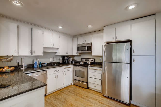 A modern kitchen with white cabinets and stainless steel appliances.