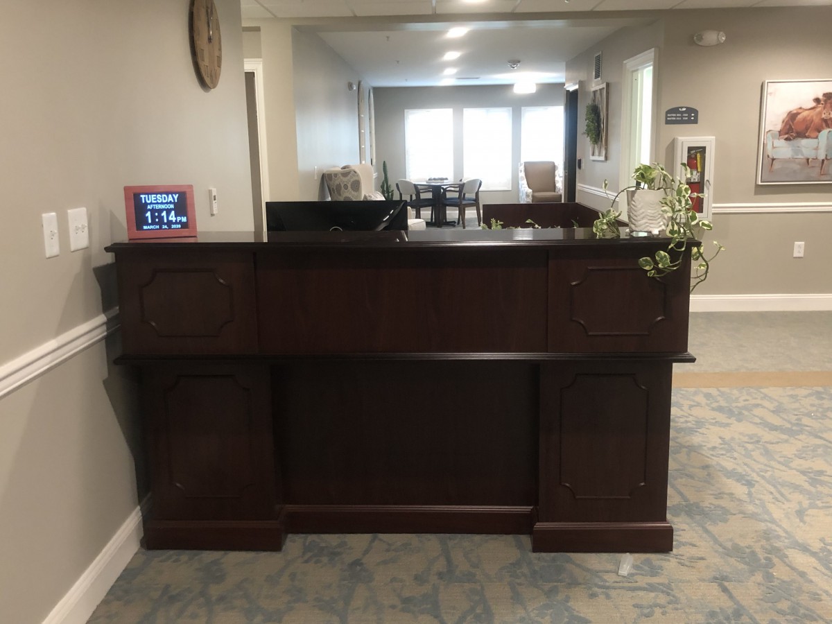 A wooden reception desk in a lobby area with a view of seating arrangements in the background.