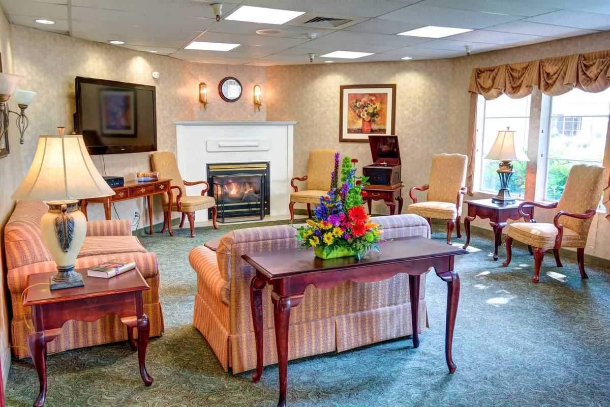 A cozy living room with a fireplace, comfortable seating, and colorful floral decorations.