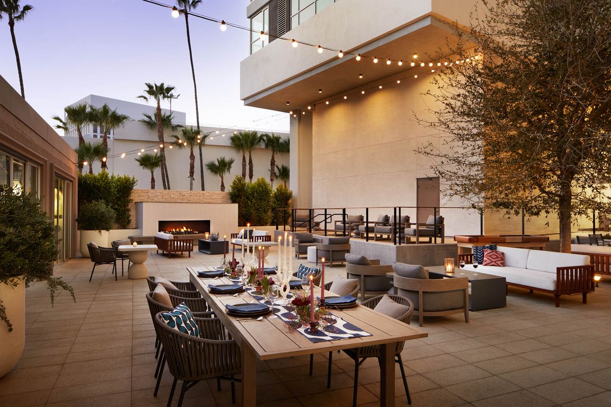 An elegant outdoor patio dining area with string lights and set tables for an evening gathering.
