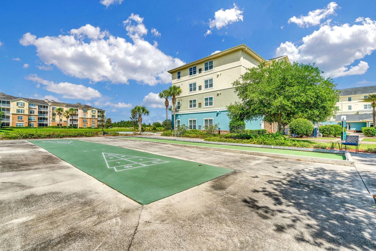 A residential building with a nearby basketball court under a partly cloudy sky.