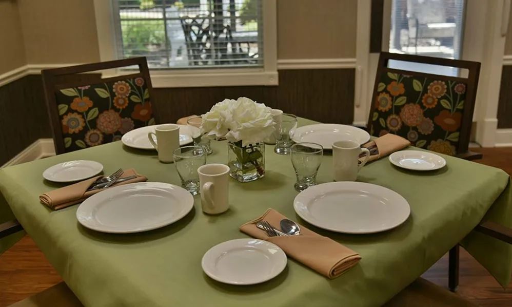 A neatly set dining table with plates, mugs, and a floral centerpiece.