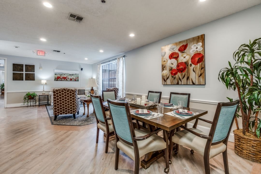 A well-appointed dining room with elegant seating and floral artwork on the wall.