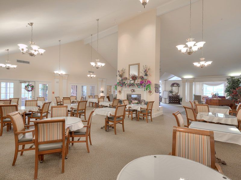A spacious dining room with elegant chandeliers and neatly arranged tables and chairs.