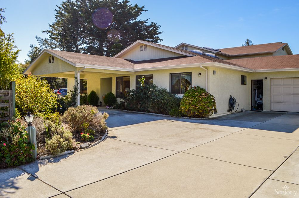 A suburban house with a neatly maintained front yard and spacious driveway on a sunny day.