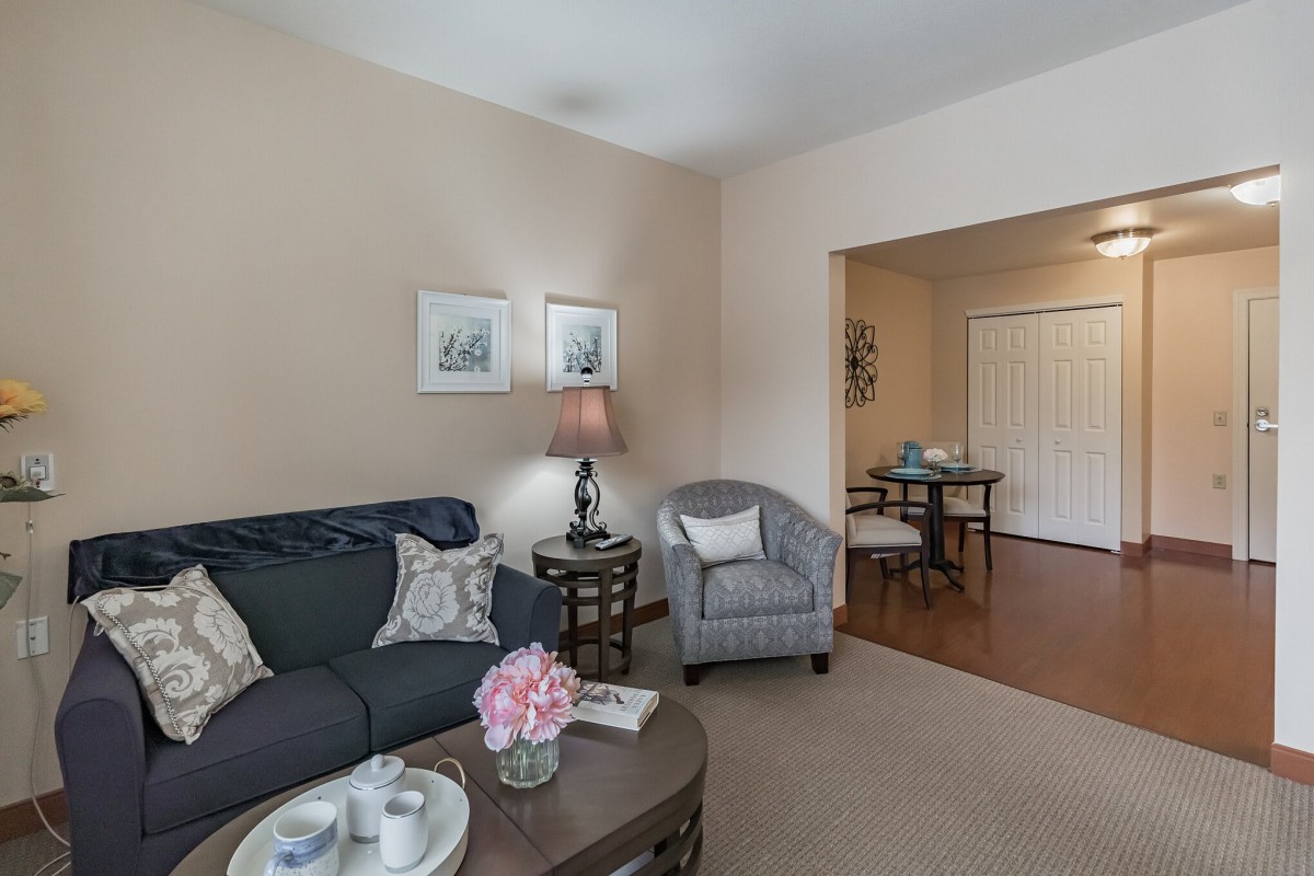 A cozy living room with a sofa, armchair, and coffee table decorated with flowers.