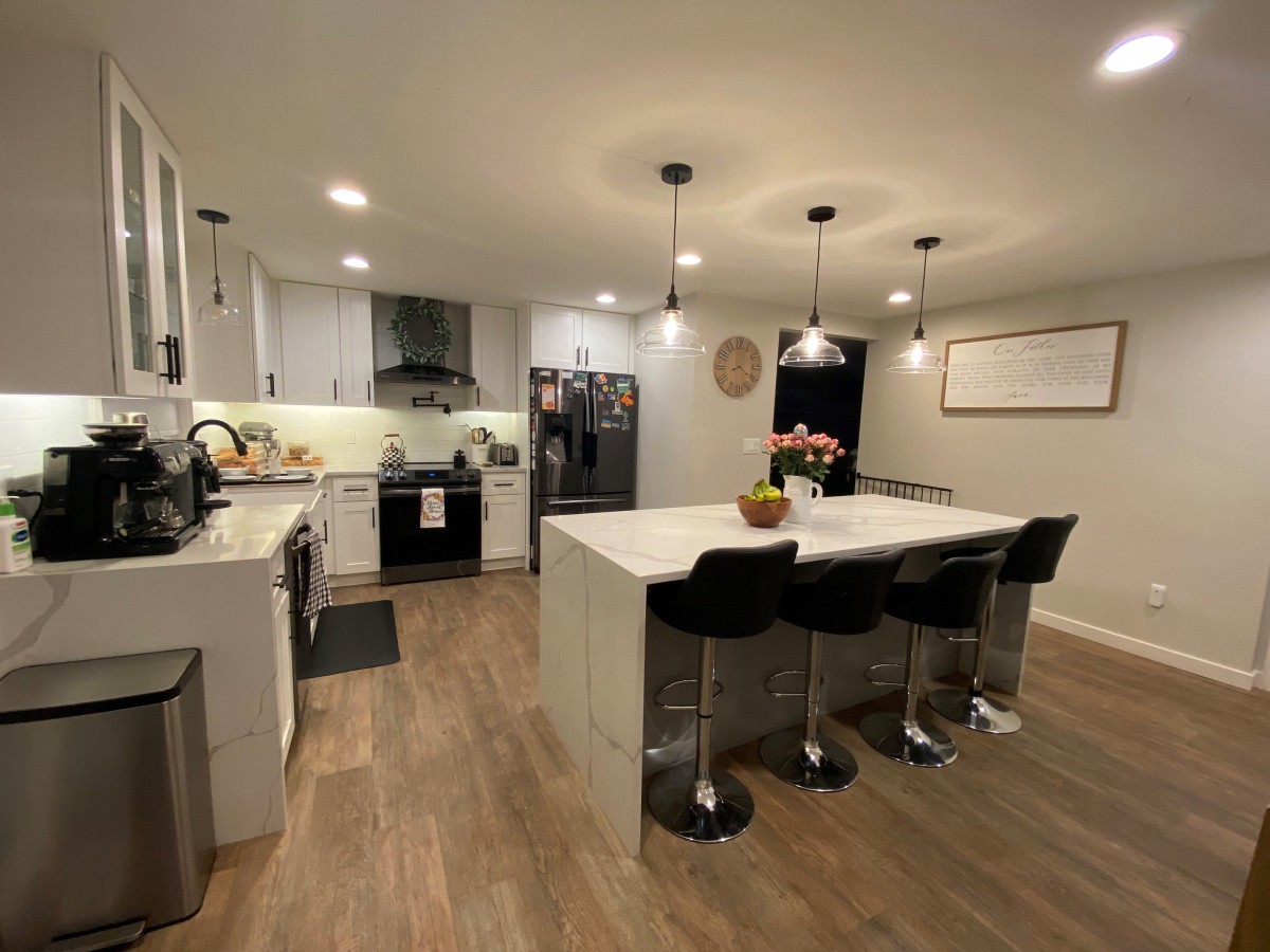 A modern kitchen with an island counter, pendant lighting, and sleek stainless steel appliances.
