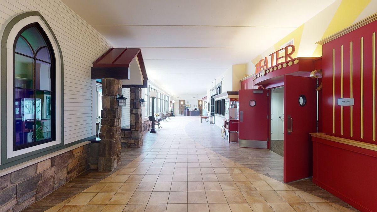 An empty corridor inside a shopping mall with tiled flooring and storefronts along the sides.