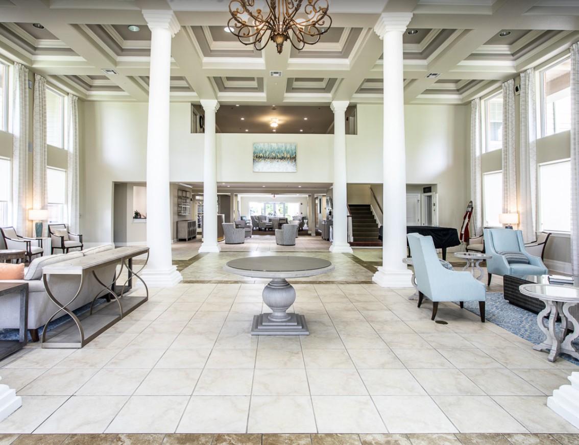 A luxurious and spacious lobby featuring large columns, elegant chandeliers, and comfortable seating.