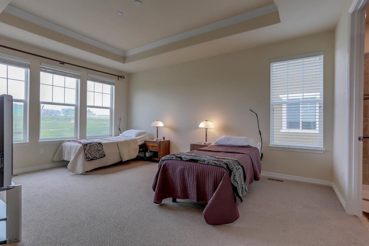 A spacious bedroom with twin beds, large windows, and cozy lighting.