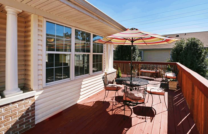 A sunny outdoor deck with patio furniture and an umbrella.