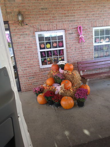 A cozy autumn display featuring pumpkins, hay, and flowers.