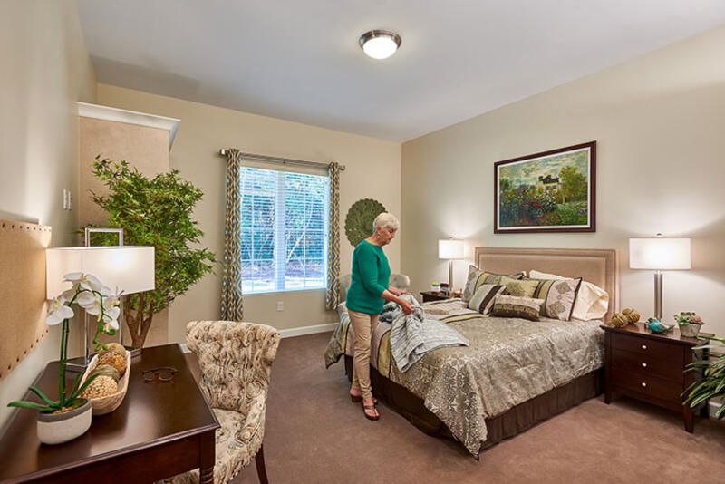 A person is tidying up a well-decorated bedroom with elegant furnishings.