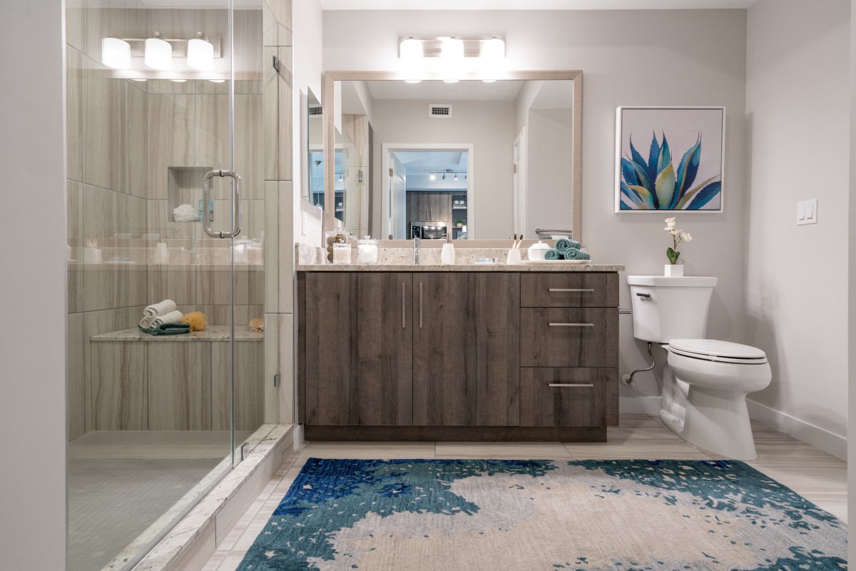 A modern bathroom with a large mirror, wooden vanity, and decorative elements.