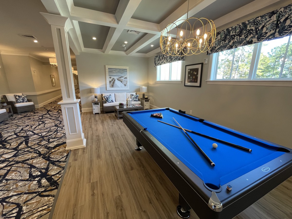 A stylish recreation room featuring a blue pool table and elegant chandelier.
