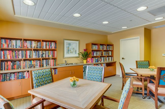 A cozy library with bookshelves, tables, and chairs for reading.
