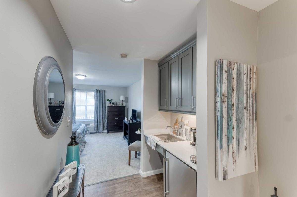 A modern interior with a compact kitchenette and hallway leading to a living space.