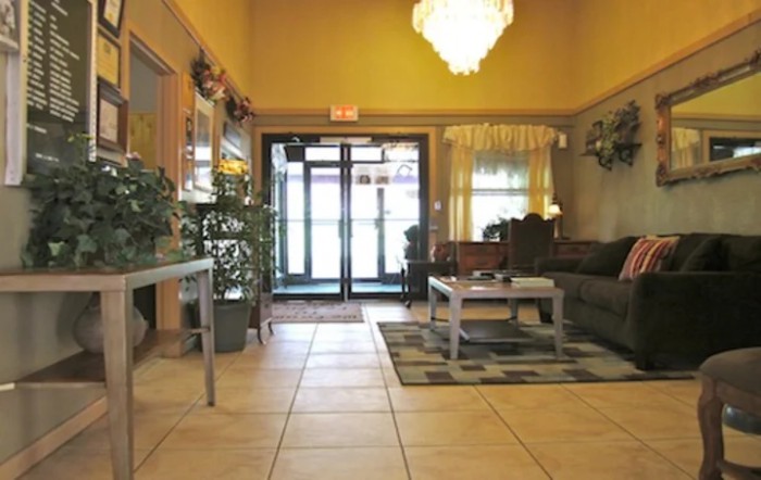 A cozy lobby area with a seating arrangement, chandelier, and potted plants.