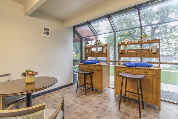 A cozy dining area with wooden furniture and large windows letting in natural light.